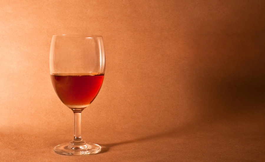 A glass of wine and an orange background