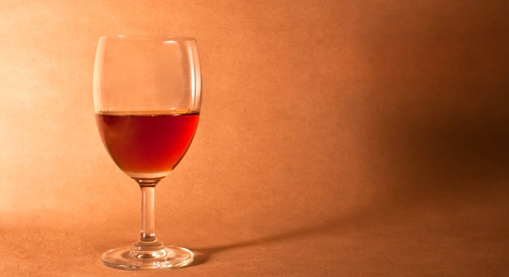 A glass of red wine on the foreground and a orange background