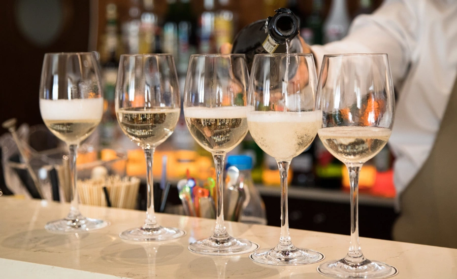 A barman who pours wine on five glasses.