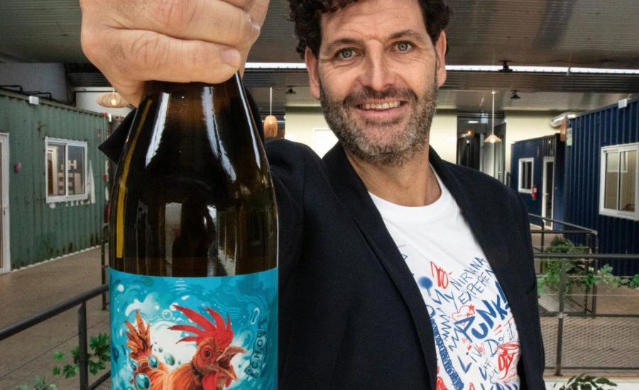 Un homme tenant une bouteille de vin en nous regardant