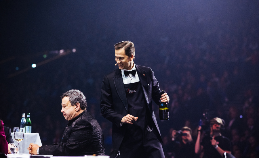sommelier apportant à des professionnels sa bouteille de vin à déguster dans une salle de spectacle avec la salle remplie de spectateurs
