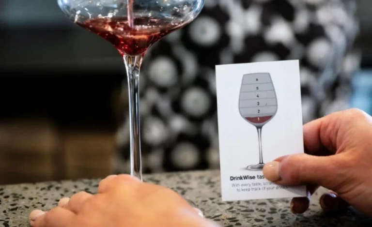 Mains tenant un verre de vin d'une main et de l'autre une carte avec un verre de vin dessiné