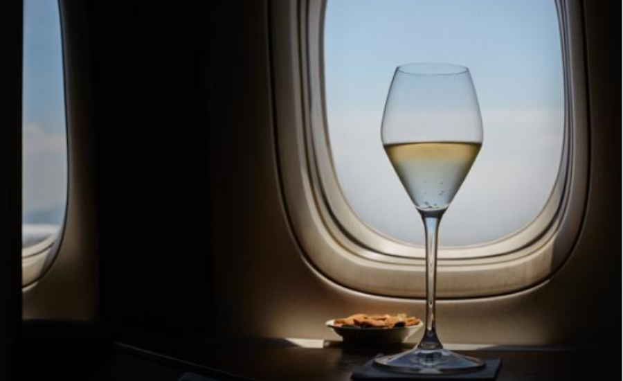 A glass of white wine on a table on an airplane