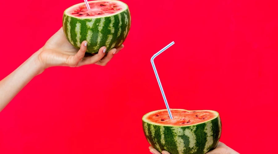 Mains qui tiennent des pastèques sur un fond rouge