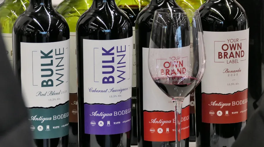 Bottles of bulk wine and a glass of wine.